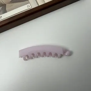 Elegante macaronroze bananenhaarklem met tanden voor een stevige grip op de paardenstaart