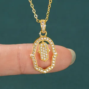 Close-up of a hollow Hamsa hand pendant necklace in 14k gold with sparkling stones