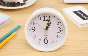 Minimalist white round alarm clock displayed on a wooden desk with colorful pencils
