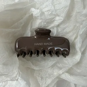 Detailopname van een bruine haarklem met Hand Made opdruk op wit zijdevloeipapier