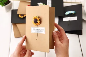 Handmade kraft paper greeting card with a dried sunflower and 'Best wishes' note.