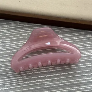 Detailed view of a minimalist pink hair claw clip with a glossy finish.
