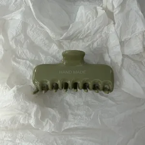 Dettaglio macro della molletta per capelli verde salvia con scritta HAND MADE