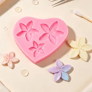 Close-up view of a heart-shaped silicone mold featuring handmade frangipani resin flowers.