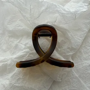 Detailed view of a minimalist amber tortoiseshell hair claw clip with a loop design.