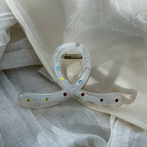 Close-up detail of an elegant white knot hair claw clip decorated with colorful rhinestones
