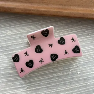 Close-up detail of a pink macaron square hair claw clip featuring heart and bow print designs.