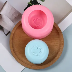 Close-up of pink silicone mold and blue soap with embossed baby footprint and text.