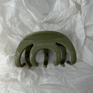 Vista ravvicinata di una molletta per capelli verde oliva con incisione HAND MADE