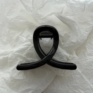 Detailed close-up of a minimalist black claw hair clip on a textured white background