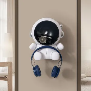 Creative astronaut wall-mounted shelf holding headphones and watch for home decoration.
