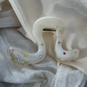 Detail shot of creamy white hair claw clip with colorful rhinestone accents on fabric