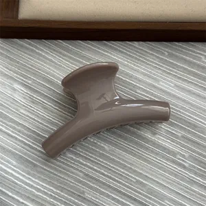 Detailed close-up view of a small jelly grey arched hair claw clip on textured background