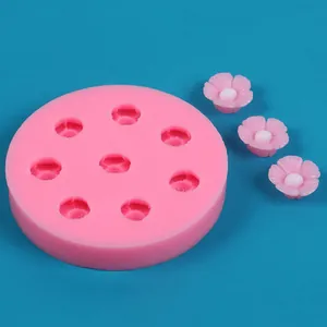 Detail of a pink sakura flower silicone mold showing finished floral resin pieces