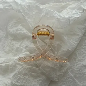 Detailed close-up of translucent champagne jelly hair claw clip on white textured paper