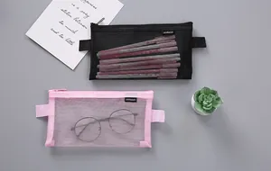 Top view of two mesh pencil cases in pink and black with stationery and plant props.