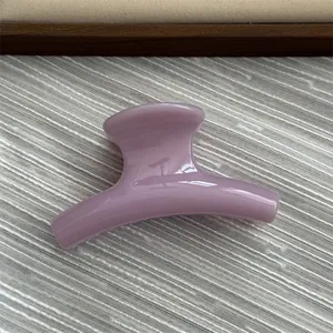 Close-up of small purple jelly hair claw clip with smooth curved design and glossy finish