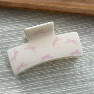 Macro view of a sweet cream square hair claw clip featuring pink bow and dot patterns