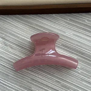 Detail of a pink jelly textured curved hair claw clip on a minimalist background.