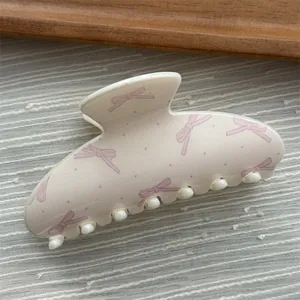 Detailed macro view of a pastel hair claw clip with pink bow and polka dot patterns