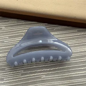 Detail view of a light blue minimalist hair claw clip on textured background surface