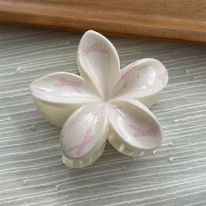 Detailed close-up of a floral hair claw clip with pink bow prints on a white base