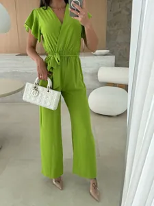 Macro view of the V-neck and ruffled sleeve detail of the lime green jumpsuit