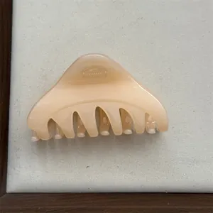 Side view of a glossy cream triangular hair claw clip for elegant half-up hairstyles