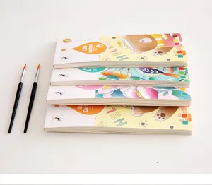 Side view of a stack of portable watercolor painting books with two brushes