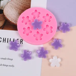 Macro view of pink silicone mold featuring finished purple and white resin five-petal flowers