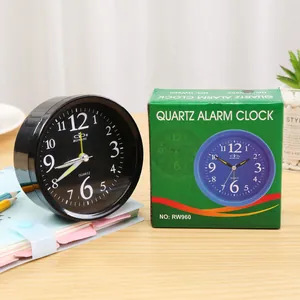 Minimalist black round quartz alarm clock shown with its green retail packaging box