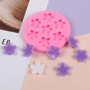 Detail view of pink five-petal flower silicone mold with finished purple resin craft pieces