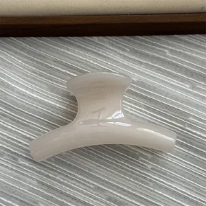 Close-up detail of a small cream-colored curved hair claw clip with a glossy finish