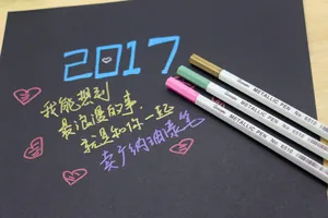 Detailed view of metallic DIY pens writing on black cardstock for photo albums