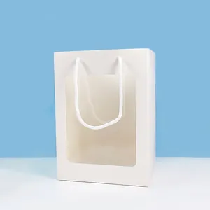 Detailweergave van witte papieren cadeauzak met groot transparant venster en stevige handvatten.