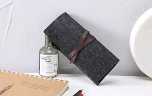 Dettaglio di un astuccio arrotolabile in feltro nero con cinturino marrone in ufficio.
