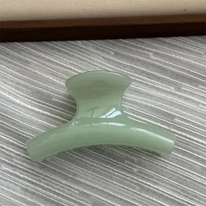 Macro view of a small jelly green curved hair claw clip on textured background