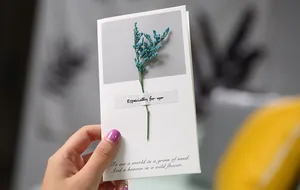 Detail view of handmade greeting card featuring a real blue dried flower