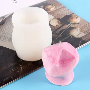 Detail view of abstract face silicone mold and pink scented candle on blue surface