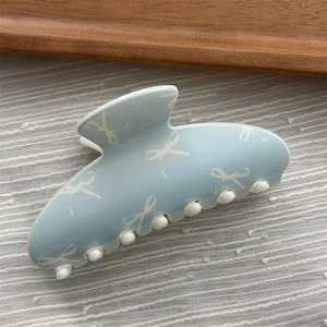Macro detail view of a macaron blue hair claw clip with sweet white bow pattern style