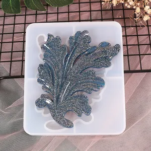 Detalle del molde de silicona en forma de hoja con pieza de resina azul brillante