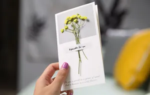 Close-up of a beautiful handmade greeting card featuring real dried yellow flowers and poetry