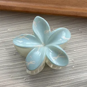 Close-up detail of a sweet light blue flower shaped hair claw clip with white bow patterns