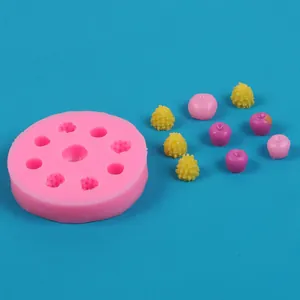 Nahaufnahme der rosa Silikonform für Obst mit bunten Harz-Apfel- und Beeren-Zubehör