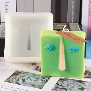 Close-up of abstract face silicone mold with a finished green creative handmade candle