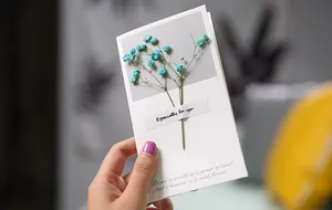 Elegant handmade greeting card featuring dried blue gypsophila flowers held in hand