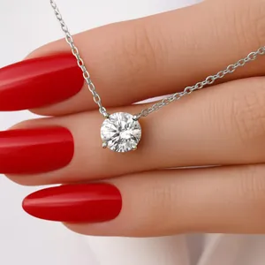 Κοντινό πλάνο μενταγιόν Moissanite με μονόπετρο που κρατιέται από κόκκινα νύχια
