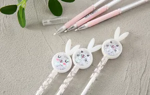 Close-up of pink bunny-themed gel pens with glitter-filled toppers on a gray stone surface.