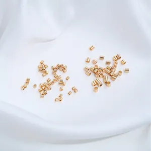 Nahaufnahme kleiner goldener Edelstahl-Quetschperlen und Positionierungsröhren für Schmuck