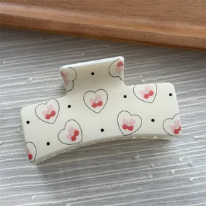 Detail view of a white square hair claw clip with heart cherry and polka dot prints.